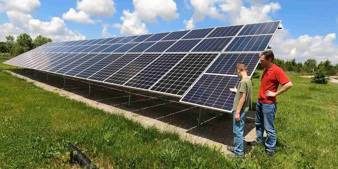A man and a child looking at rows of solar panels tilted at angles on a farm