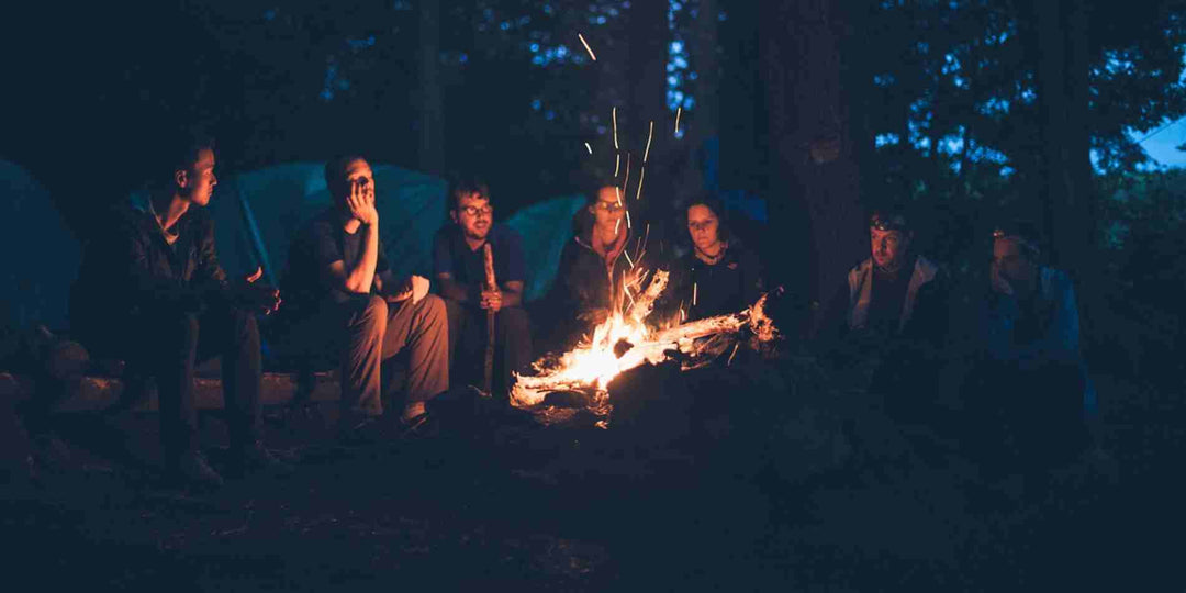 People sit facing the campfire