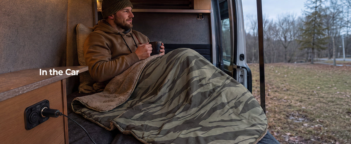 Person relaxing in a car with a warm drink and BougeRV 12V heated blanket while enjoying the outdoor view
